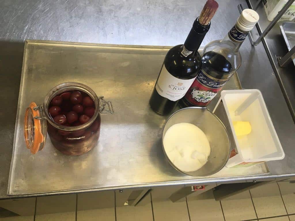 Ingrédients : Des cerises au sirop 50g de beurre 50g de sucre De la glace vanille 100g de cerises au sirop 6 cl de crème de cassis 15 cl de bon porto (ici un Porto Quinta St José Vintage Port 2016)